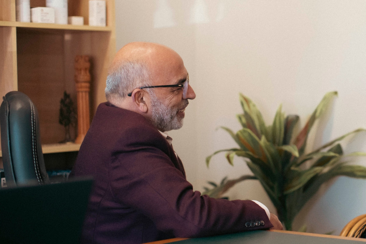 Dr. Ajit hands clasped together with his Ancient Secrets book in background