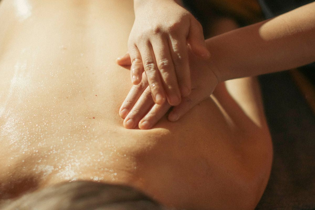 Therapist applying ayurvedic massage technique on clients back during therapy