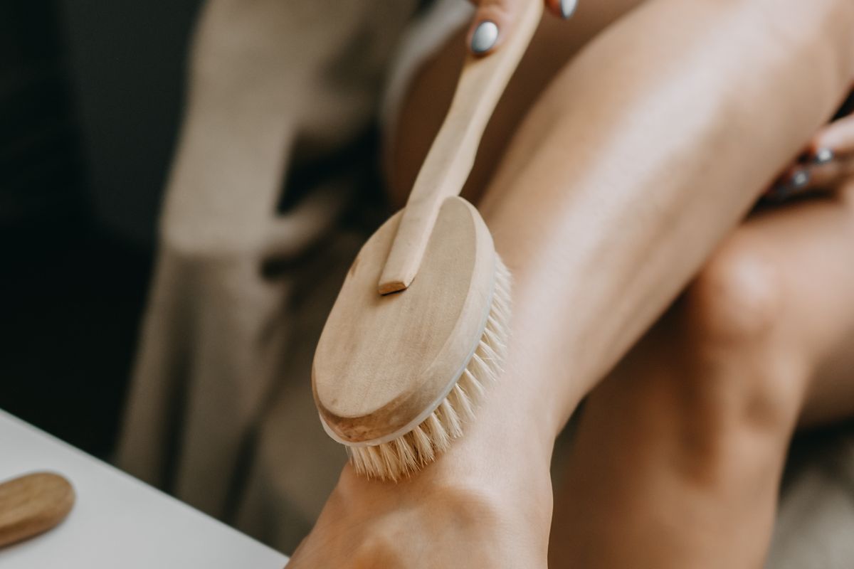 woman using dry body brush on her legs