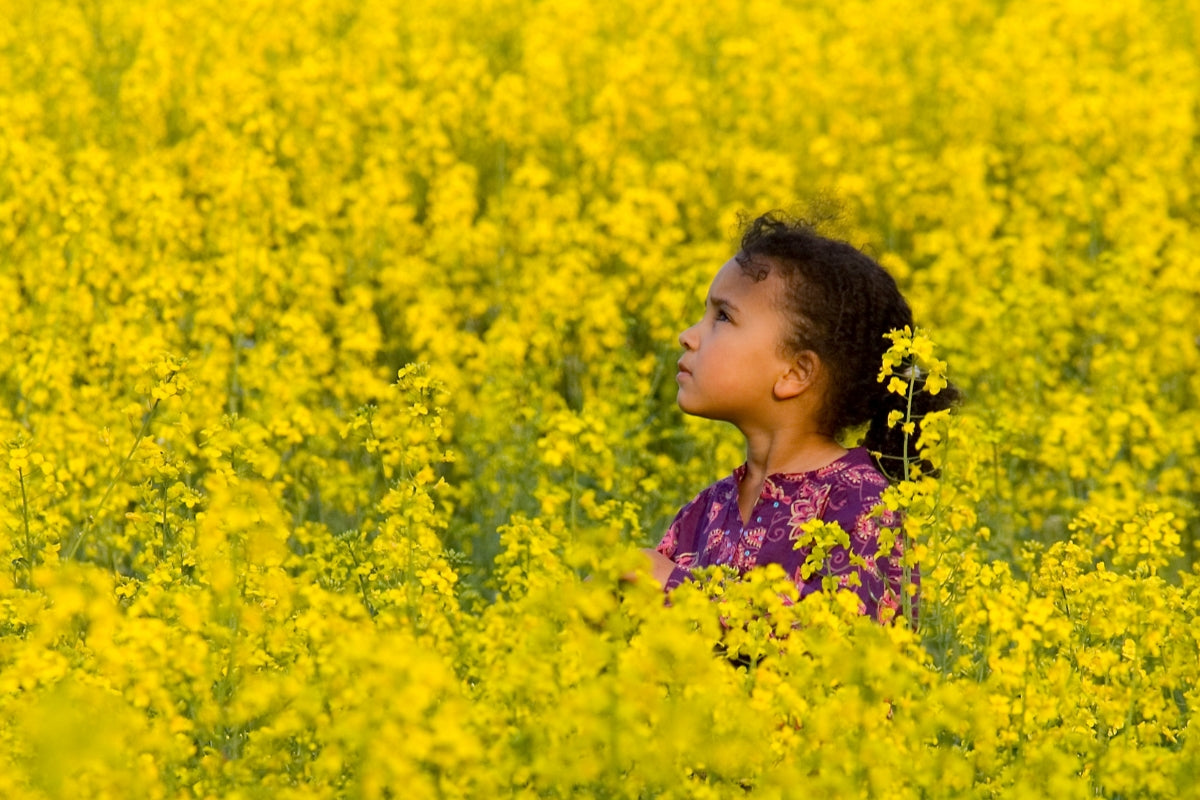 woman running through field of yellow flowers