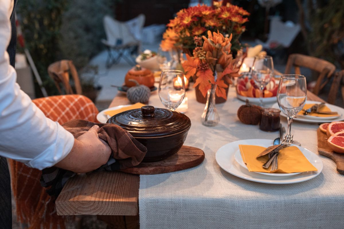 man placing crock pot on table in preparation for holiday feast