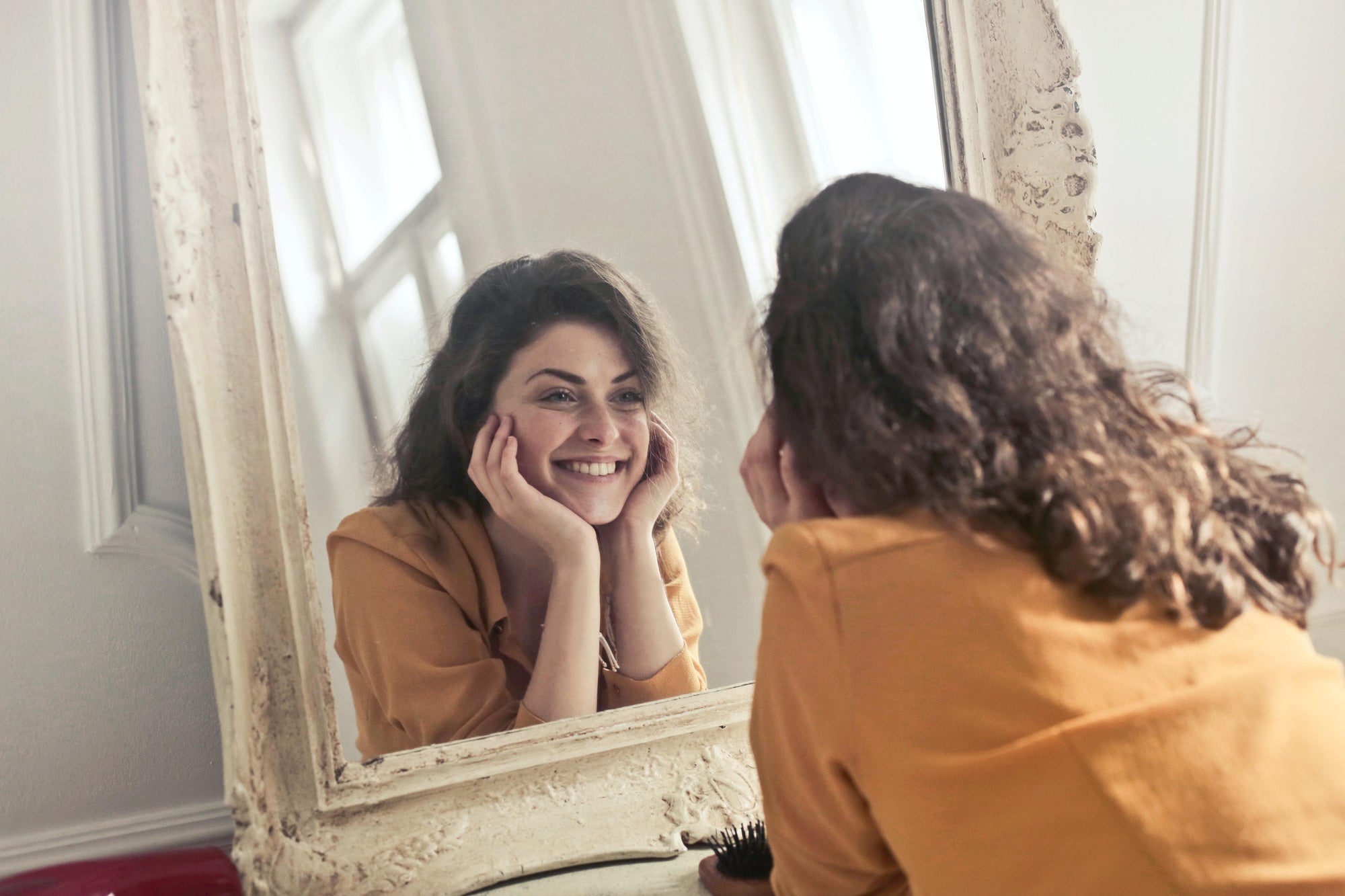 woman smiling at herself in mirror