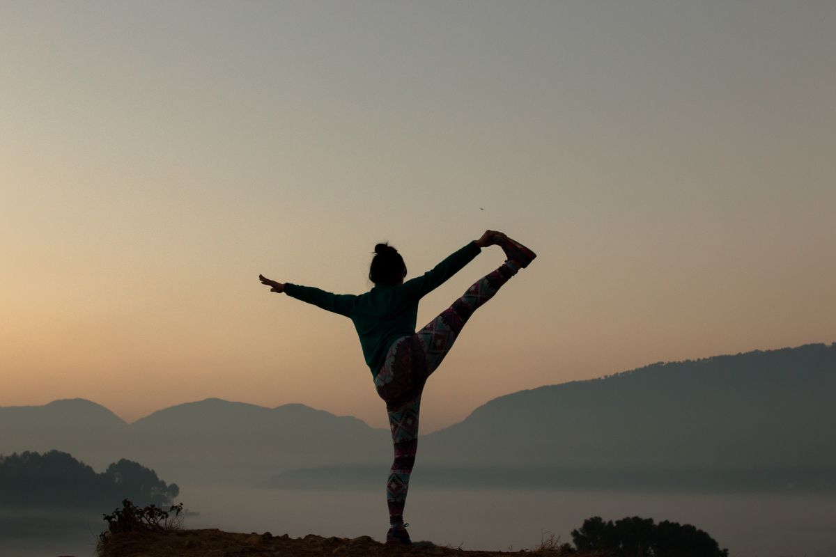 woman doing a yoga pose on a mountain on a winters morning